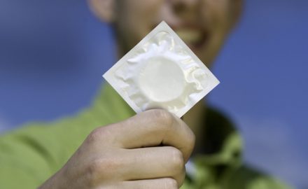 Teen holding a wrapped condom. AIDS risks are real for teens.