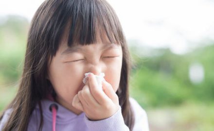 Allergies, Colds, Covid -- how can a parent tell them apart? Young Asian girl crinkling her nose and closing her eyes like she's going to sneeze.
