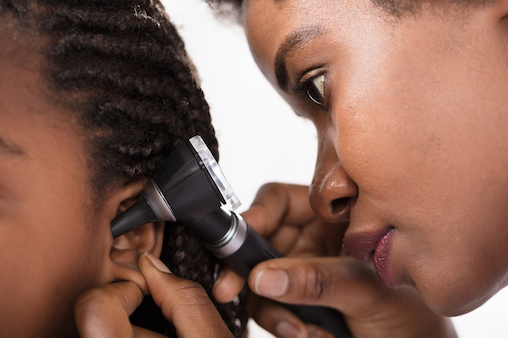 African American doctor looking into the ears of a young girl. Antibiotics are often prescribed for ear infections. Some times needlessly. This is part of the reason we have an antibiotic epidemic.