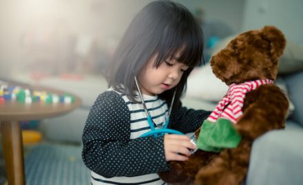 Young Asian Girl listening to her teddy bear's heart with a stethoscope. Antibiotic Related ER Visits.