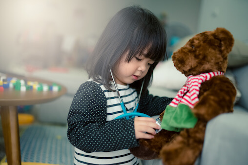 Young Asian Girl listening to her teddy bear's heart with a stethoscope. Antibiotic Related ER Visits.