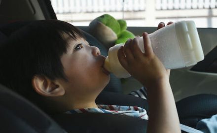 Asian toddler in a car seat drinking from a baby bottle. How do go about baby bottle weaning?