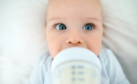 Baby drinking milk from a baby bottle with an odd look on his face. Could it be Galactosemia?