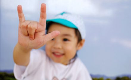 Adorable smiling Asian baby sign language.