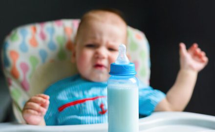 Baby looking at a bottle in disgust.