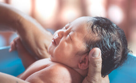 Bathing baby safely in parent's arms with head supported.