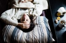 Sick woman laying in bed. Breast Feeding When Mom Feels Sick?