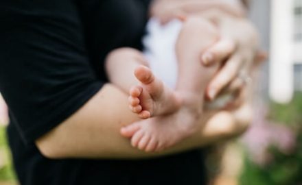 Is Breastfeeding with Propionic Acidemia recommended? Mother breastfeeding her baby with baby's feet showing and body out of focus.