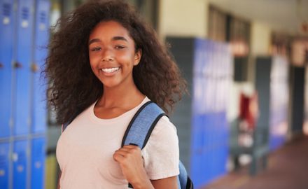 African American girl at high school in front of lockers. Calcium for teens is very important.