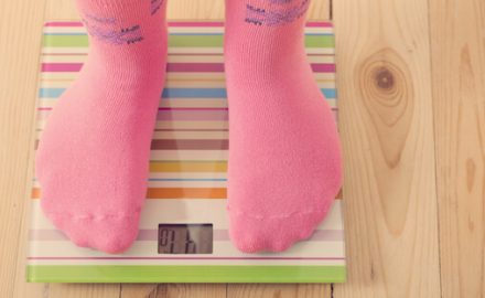 Child in pink socks on a bathroom scale. Childhood obesity is a real problem in the US.