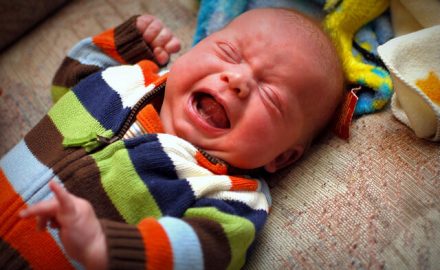 Crying baby in a stripped onesie