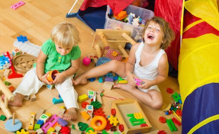 Two happy cute little girls playing with blocks. Contact transmission can happen through play.