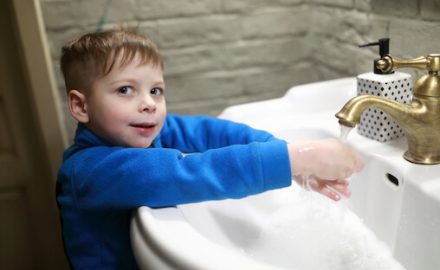 Young boy washing his hands to protect against coronavirus COVID-19