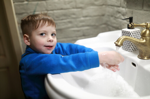 Young boy washing his hands to protect against coronavirus COVID-19