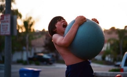 Angry boy screaming while holding a blue ball. For parents this can be difficult behavior.