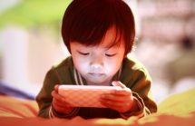 Small boy looking intently at a smartphone screen. Is reducing blue light an effective ADHD interventions?