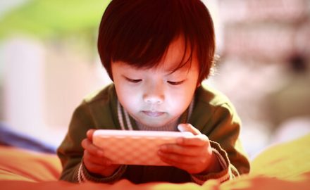 Small boy looking intently at a smartphone screen. Is reducing blue light an effective ADHD interventions?