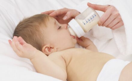 Baby taking milk from a bottle. Formula and Constipation