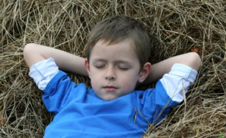 Boy sleeping on a bed of hay. Fragile x syndrome.