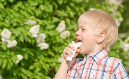 Young boy demonstrating asthma inhaler use.