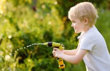 Boy playing in the backyard with a waterhose. Does this yard have just a little roundup to kill the weeds?