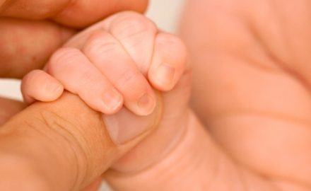 Adult holding a babys fingers. There are lasting Effects of Fetal Alcohol Syndrome