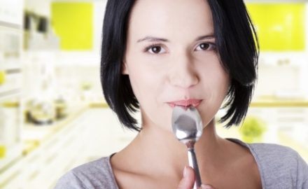 Young woman in kitchen with a spoon. Mom's Diet while Breast Feeding.