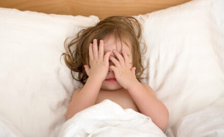 Child in bed covering her eyes after a night terror