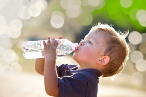 Young boy outside, drinking from a water bottle