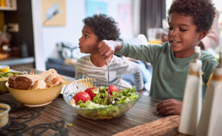 Two African American children eating. One school age, one preschool healthy foods.