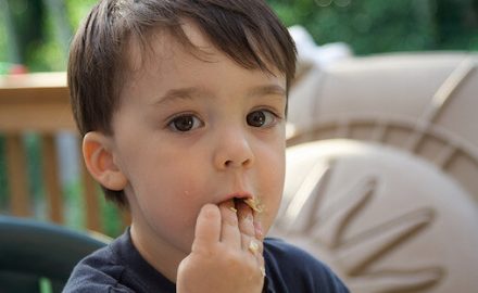 Child eating cereal with his hands.
