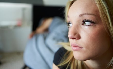 Sex should not hurt. Teenage girl crying in the foreground while boyfriend sleeps in background.