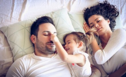 Mother, father and child in bed. The child is awake and parents are trying to sleep. Sleep and the family bed can be confusing.