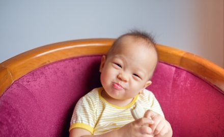 Asian baby eating a banana. Bananas are a great food for baby when starting solids.