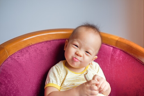 Asian baby eating a banana. Bananas are a great food for baby when starting solids.