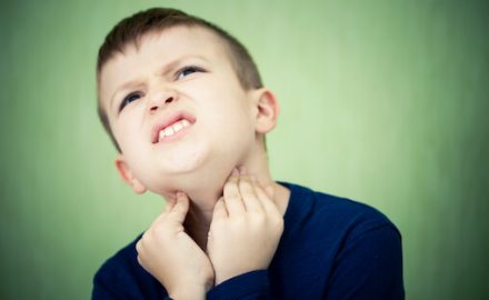 Tween boy holding his throat with a pained look on his fact. Could this be strep throat?