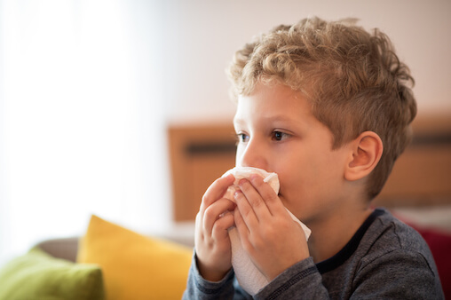Boy blowing his nose. Stuffy nose and cough for kids.