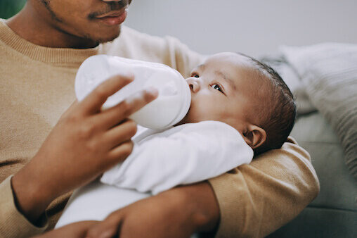 Father feeding an infant a bottle - surprising infant formula ingredients