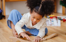 Girl playing with a wooden toy train. Toy selection is an issue for parents.