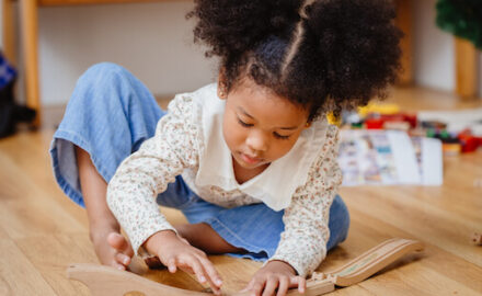 Girl playing with a wooden toy train. Toy selection is an issue for parents.