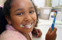 Young black girl brushing her teeth. Unusual breath odors in children with good dental hygiene should see a pediatrician.