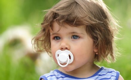 Little girl with pacifier in her mouth. Weaning from a pacifier.