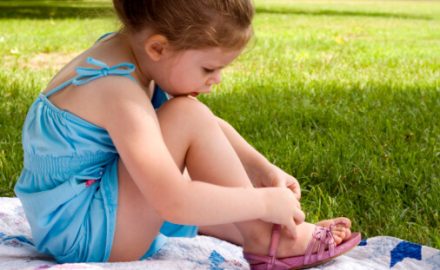 Child sitting on a blanket on the grass. What are pinworms?