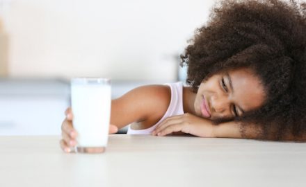 School age girl refusing to drink a glass of milk.