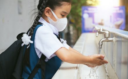 Asian school girl in uniform washing her hands. Is she using antibacterial soap?
