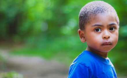 Young African American boy in bright blue shirt. Middle ear fluid can cause hearing loss and learning delay.
