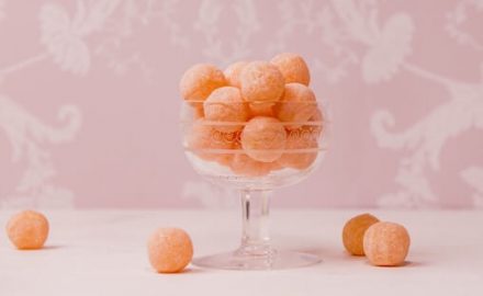 Bowl of orange hard candy with a pink background. Hard candy is a choking hazard!