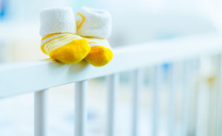 Image of an empty crib with baby slippers. Trisomy 13 is a genetic condition that is likely fatal.